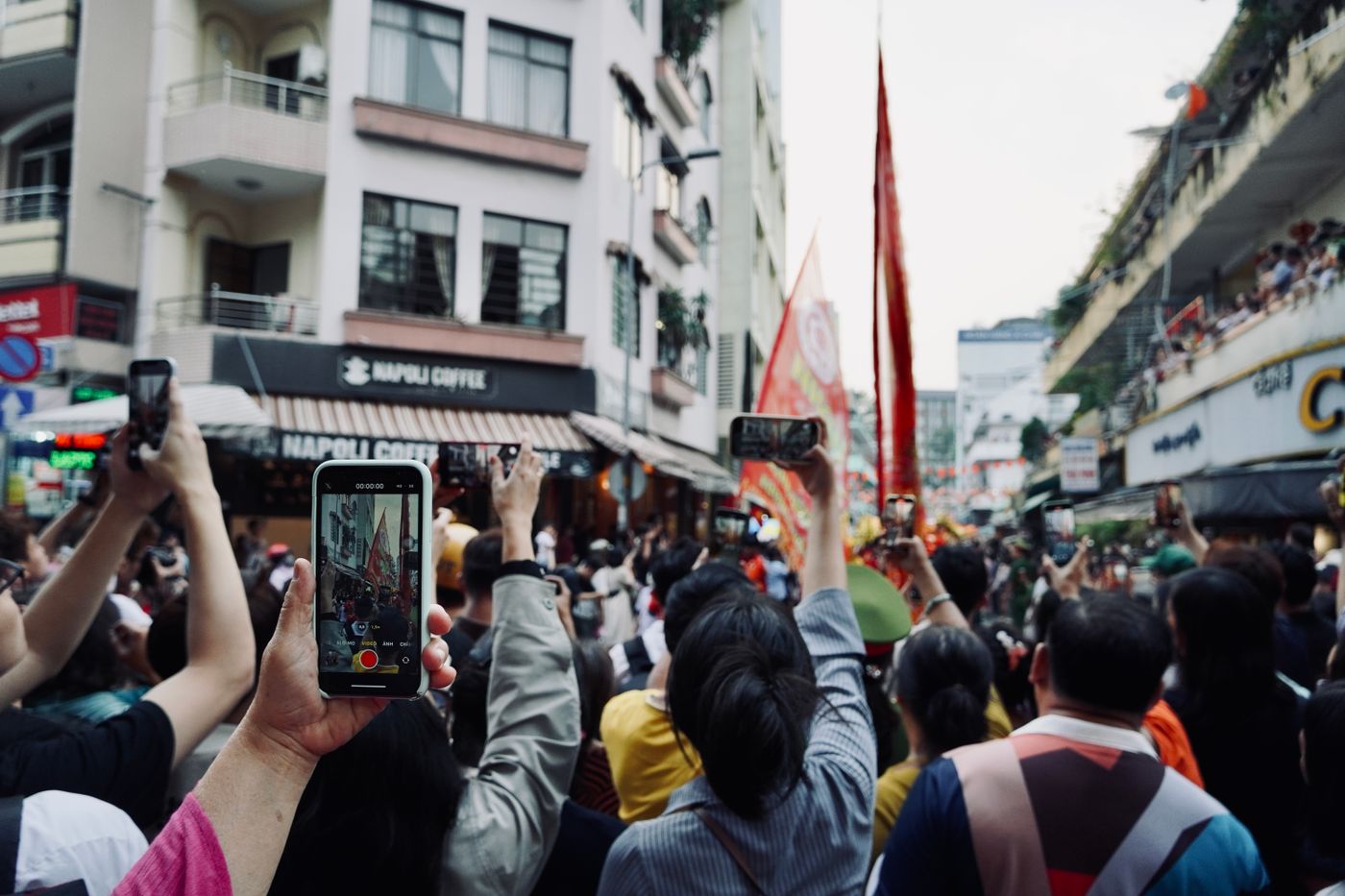 A crowd at a street event, with visitors holding up phones