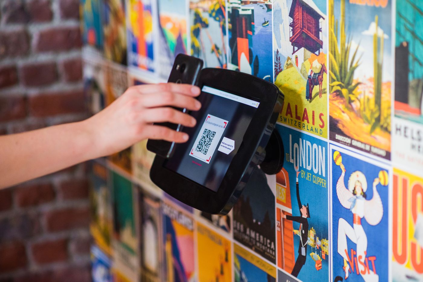 A visitor holding a QR code on a phone up to a scanner
